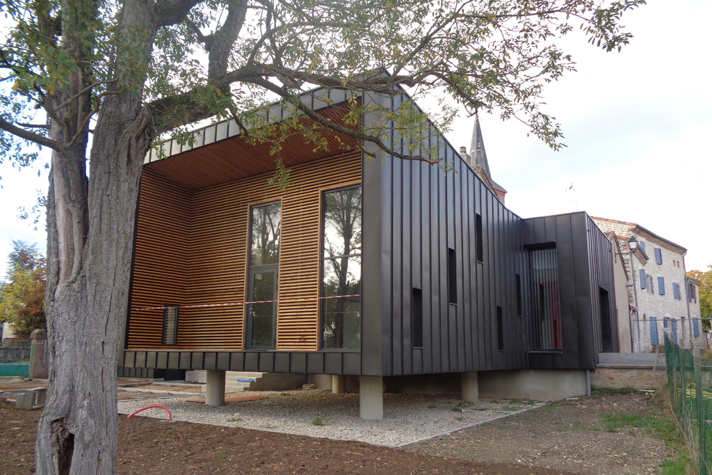 Transformation de l'ancienne école de Taïx en Maison des associations avec une extension en ossature bois habillée en zinc à joints de bouts de type anthrazinc.