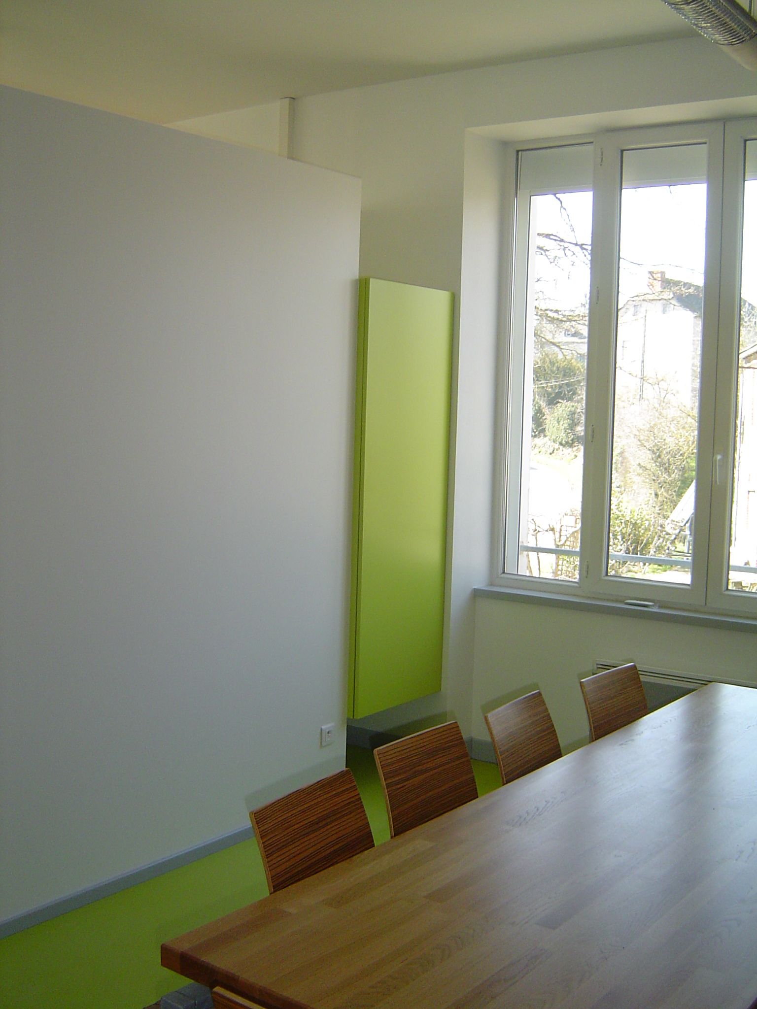 Vue sur le bloc de rangement traité comme un meuble qui sépare l'accueil de la salle de réunion du conseil