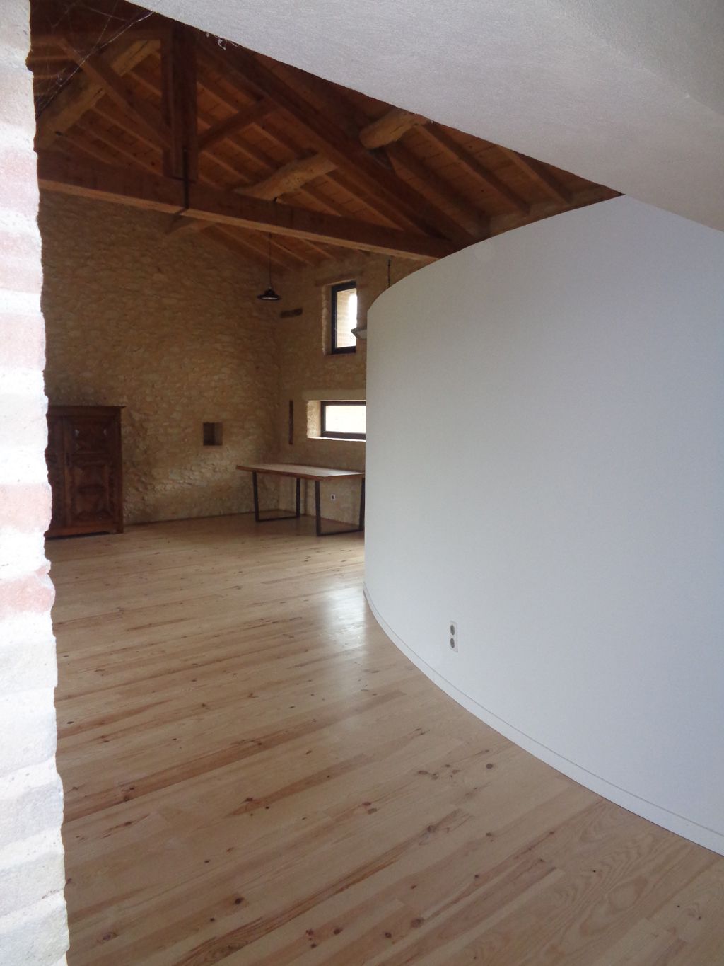Local professionnel avec murs à la chaux et charpentes bois apparentes existantes, sol en parquet bois verni isolé et volume courbe en plaque de plâtre intégrant les sanitaires